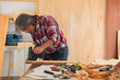 © Rakchanok - Elderly lifestyle working after retirement concept, healthy senior carpenter happy working in carpentry home studio, aged man with silver hair create his DIY handmade using a chainsaw to cut woodwork