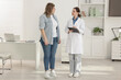 © New Africa - Weight loss. Overweight woman standing on scales during consultation with nutritionist in clinic