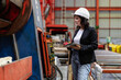 © Nassorn - Woman engineer manager working at steel production factory. Female inspector wears safety hard hat holding clipboard checking metal equipment and machinery maintenance in workshop. Quality control.