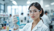 © Ornpitchayawee - Female Scientist in Laboratory Holding Test Tube with Blue Liquid, Wearing Protective Gear and Glasses, Research and Experimentation Concept
