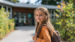 © Nataliia Pyzhova - Smiling young schoolgirl with braided hair and backpack standing outdoors near school entrance. First day of school atmosphere. Confident and happy.