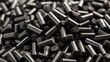 © SY - Shiny, dark, cylindrical pellets are piled in a dense, textured close-up. It's useful for illustrating industrial processes or material science topics.