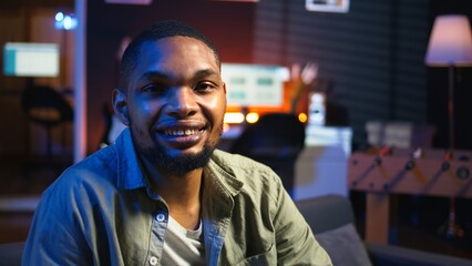 Poster - Portrait of african american person smiling and working in his living room, using laptop to solve remote freelancing tasks as a self employed guy. Young adult feels relaxed at home. Camera A.