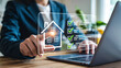 © Design Store - Person interacting with a digital interface displaying a house icon and a checklist with green checkmarks next to tasks on a laptop