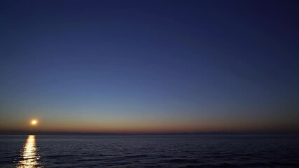 Wall Mural - Warm golden sunlight glimmering across peaceful ocean surface, painting sky with vibrant orange yellow gradient during serene dawn moment