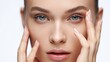 © jesus - Retrato macro del rostro de una modelo con piel radiante y maquillaje nude, aplicando un tratamiento facial o crema para los ojos, ideal para publicidad de productos antienvejecimiento o dermatología