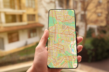 Woman looking at city map on her mobile phone outdoors, closeup