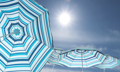 Wall Mural - bright striped beach umbrellas against blue sky on sunny day