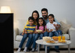 © Bold Frame Media - Joyful Indian Family Watching TV Together, Enjoying Snacks and Quality Time in a Cozy Home Environment