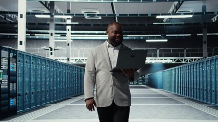Poster - Smiling server room engineer performing maintenance on server racks using software on laptop. Happy data center IT professional upgrading blade server components using notebook, camera A