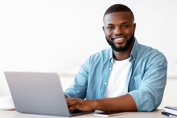 Aufkleber - Portrait Of Happy Successful Black Freelancer Guy Posing At Desk With Laptop, Positive Millenial African American Man Smiling At Camera While Working Online On Computer In Home Office, Free Space