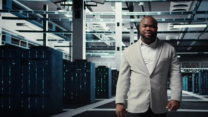 Poster - Smiling manager in data center doing checkup on hardware to avoid downtime. Happy african american supervisor overseeing server room infrastructure supercomputers, camera A