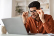© Prostock-studio - Error. Portrait of confused Arab guy sitting at desk using laptop, taking off glasses looking at pc screen and squinting. Worried man reading bad negative news, having poor eyesight problems