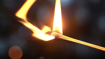 Poster - Burning Match Flame Against Blurred Dark Background Illuminating With Yellow And Orange Light
