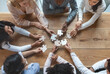 © Prostock-studio - Collaboration concept, top view of young creative multiracial team sitting around table and putting together puzzle pieces