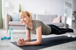 © Prostock-studio - Home training concept. Smiling senior woman doing elbow plank on yoga mat in living room. Positive mature lady doing her workout routine, exercising indoors, strengthening her core muscles
