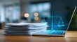 © aryuna99 - A laptop displays a glowing scales of justice graphic above a stack of papers on a wooden desk, suggesting legal tech or online justice