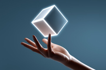 Poster - Hand reaches toward floating glowing cube casting soft light in futuristic setting. Negative space enhances focus on technology interaction