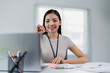 © MINAE - Young asian businesswoman working with laptop and holding pen while sitting at her desk in modern office, smiling and looking towards the laptop