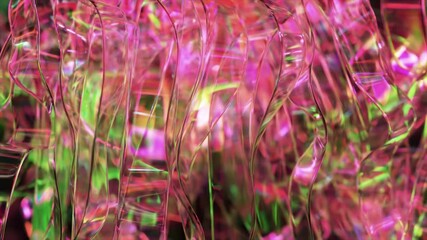 Poster - Iridescent pink and green plastic ribbons gently swaying, intertwining, reflecting light with translucent surfaces, creating dynamic color and texture composition
