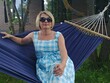 © Pavel Losevsky - Woman is sitting on a blue and white checkered dress on a hammock. She is wearing sunglasses and a blue hat