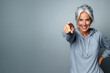 © Di Studio - Smiling mature woman in sportswear pointing at camera over light grey background with copy space. Healthy lifestyle and fitness motivation concept