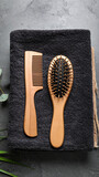 Comb and Brush on Dark Towel: A high-angle shot of a natural wooden comb and a brush with natural bristles, artfully arranged on a textured dark towel. capturing minimalist beauty