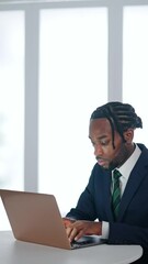 Poster - A black male business person working on a laptop at a desk in an office