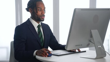 Poster - A black male business person working on a desktop PC in an office
