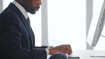 Poster - A black male business person working on a desktop PC in an office