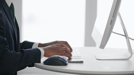 Poster - A black male business person working on a desktop PC in an office