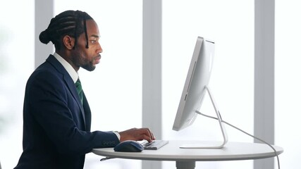 Poster - A black male business person working on a desktop PC in an office
