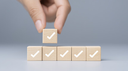 Poster - Hand placing wooden block with check mark on top of stacked blocks, symbolizing achievement, progress, and success in business or personal goals, with soft gray background
