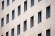 © VladyslavShcherbakov - Minimalist building facade with evenly spaced rectangular windows. Repetitive architectural geometry under daylight. Urban symmetry highlights clean modern design concept.