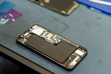 Poster - Technician Repairing a Smartphone With Opened Casing and Visible Internal Components at a Phone Repair Shop