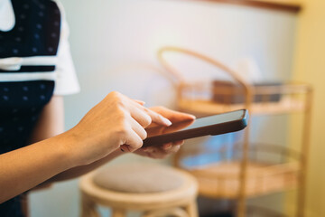 Poster - Woman using smartphone. Woman Using Smartphone in Cozy Café Setting with Natural Light and Modern Décor