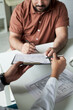 © pressmaster - Middle aged Caucasian man consulting with doctor in medical office, holding pen and signing medical documents, doctor handing clipboard with diabetes patient information, close up hands