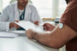 © pressmaster - Middle aged Caucasian man with continuous glucose monitor on upper arm consulting male doctor in medical office, discussing diabetes management and reviewing health records together
