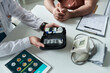 © pressmaster - Middle aged Caucasian man sitting at desk with hands folded while doctor showing diabetes management kit including glucometer and insulin pen during medical consultation