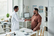 © pressmaster - Middle aged Caucasian man visiting doctor in medical office, shaking hands with young adult South Asian male physician, discussing diabetes management with medical equipment on desk