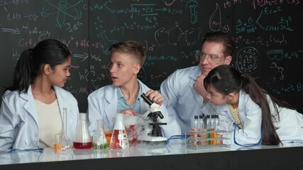 Poster - Multicultural student looking under microscope while cute girl inspect sample. Teacher looking after high school children doing experiment at blackboard with science theory in STEM class. Edification