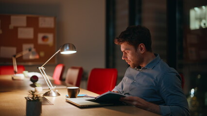 Poster - Accountant writing notebook night office under lamp light closeup. Serious man