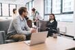 © BullRun - Young Asian woman and Caucasian man having a productive business conversation in an informal lounge area, demonstrating teamwork, leadership, and effective tech-enabled communication