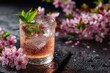 © LimeSky - Close up of a chilled spring drink in a glass featuring pink champagne cider or lemonade ice and mint with cherry blossoms above on a dark background