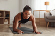 © New Africa - Sporty woman doing plank exercise on fitness mat at home