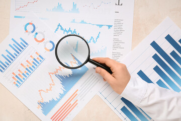 Fototapete - Female hand with magnifier and business charts on white background