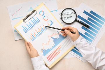 Fototapete - Female hands with magnifier, clipboard and business charts on white background