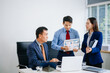 © laddawan - Asian executives discussing financial data and charts in a modern office setting. Teamwork, decision making, leadership