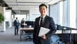 © 순단 강 - A Korean man in a suit holding a laptop computer to the right, with luxury office furniture in the blurred background