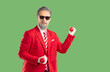 © Studio Romantic - Merry Christmas. Funny, modern Santa Claus in stylish red suit and striped tie holds dumbbells, showing how strong he is.Portrait of happy, smiling, young, eccentric Santa on isolated green background